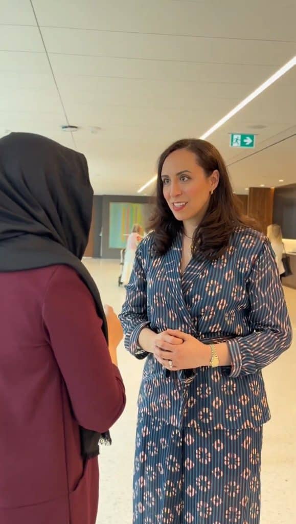 Suzanne Knight speaking at a professional event with a woman in hijab.