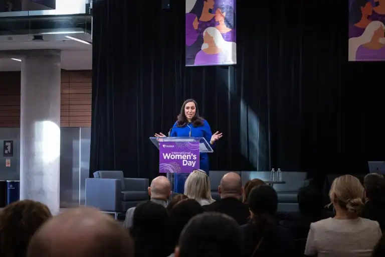 Suzanne Knight delivering the keynote at the City of Vaughan International Women's Day event, speaking from a podium.